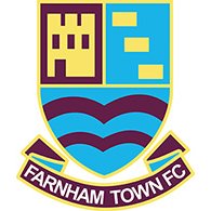 Farnham Town FC club crest featuring a shield with abstract shapes and blue wavy lines, above a banner reading FARNHAM TOWN FC—an iconic symbol often seen at their Celebrity football Match events.